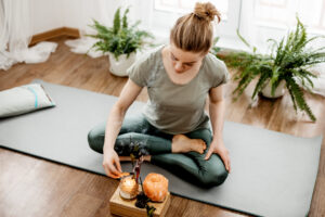 Young relaxed woman doing yoga at home with candles and incense.