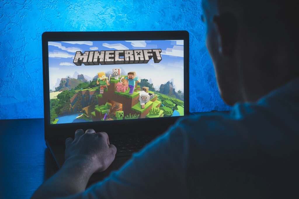 Rent a minecraft server: A person is sitting in front of a laptop with the Minecraft start screen displayed
