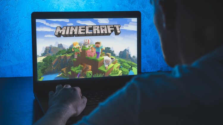 Rent a minecraft server: A person is sitting in front of a laptop with the Minecraft start screen displayed